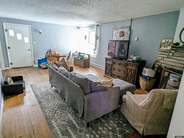 living room featuring a fireplace, baseboard heating, hardwood / wood-style floors, and a textured ceiling