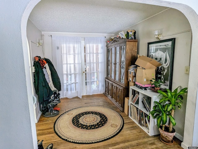 foyer entrance with wood-type flooring, a textured ceiling, and french doors