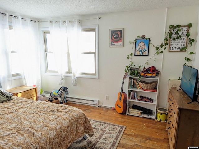 bedroom with hardwood / wood-style flooring, a baseboard radiator, and a textured ceiling