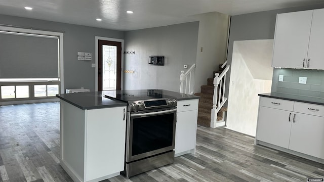 kitchen featuring backsplash, stainless steel electric range, hardwood / wood-style floors, and white cabinets