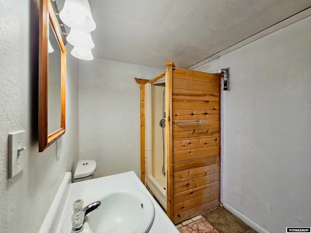 bathroom featuring sink, toilet, walk in shower, and a textured ceiling