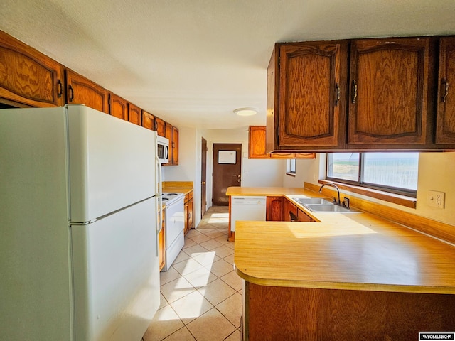 kitchen featuring light tile patterned flooring, kitchen peninsula, sink, and white appliances