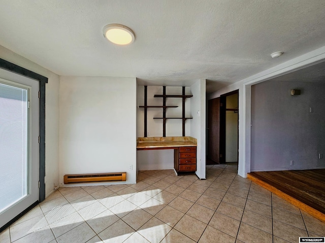 interior space with a textured ceiling and a baseboard heating unit