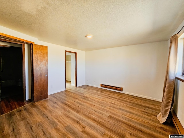 unfurnished bedroom with a closet, hardwood / wood-style flooring, a textured ceiling, and baseboard heating