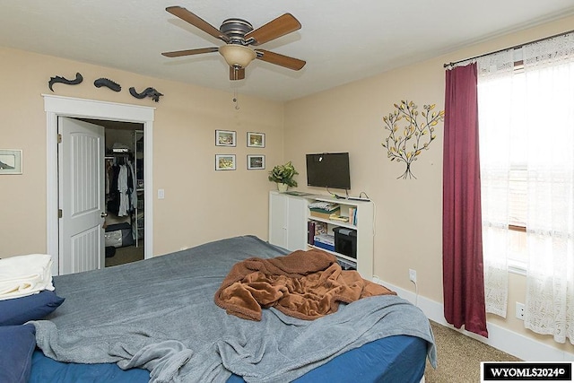 carpeted bedroom with a spacious closet and ceiling fan