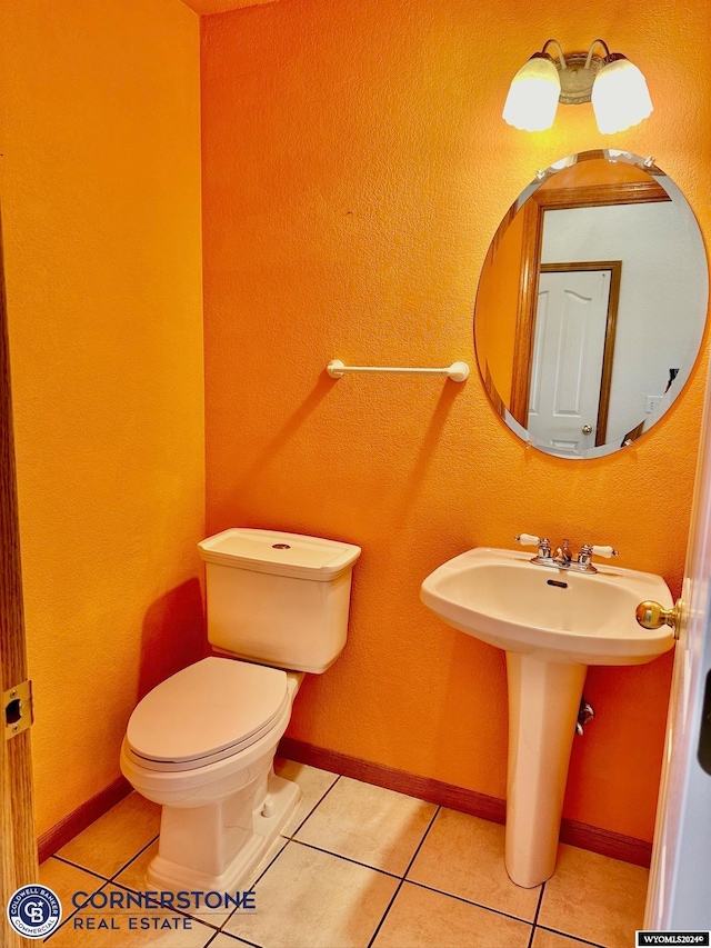 half bath with toilet, tile patterned flooring, and baseboards