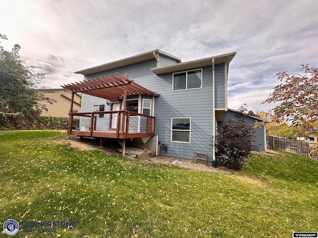 rear view of property featuring a yard, fence, a wooden deck, and a pergola