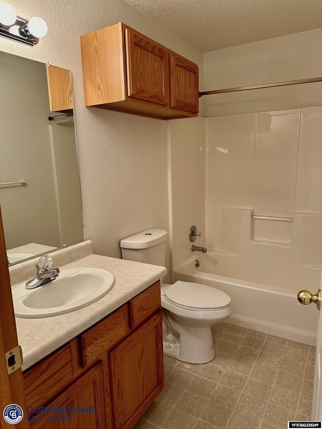 bathroom with toilet, vanity, a textured ceiling,  shower combination, and tile patterned floors