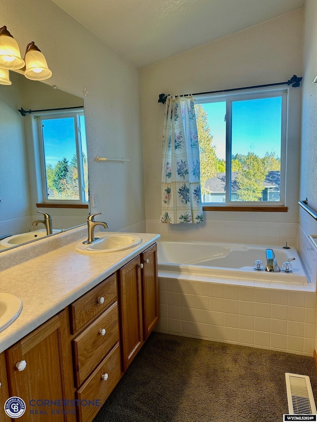 bathroom with double vanity, a garden tub, visible vents, and a sink