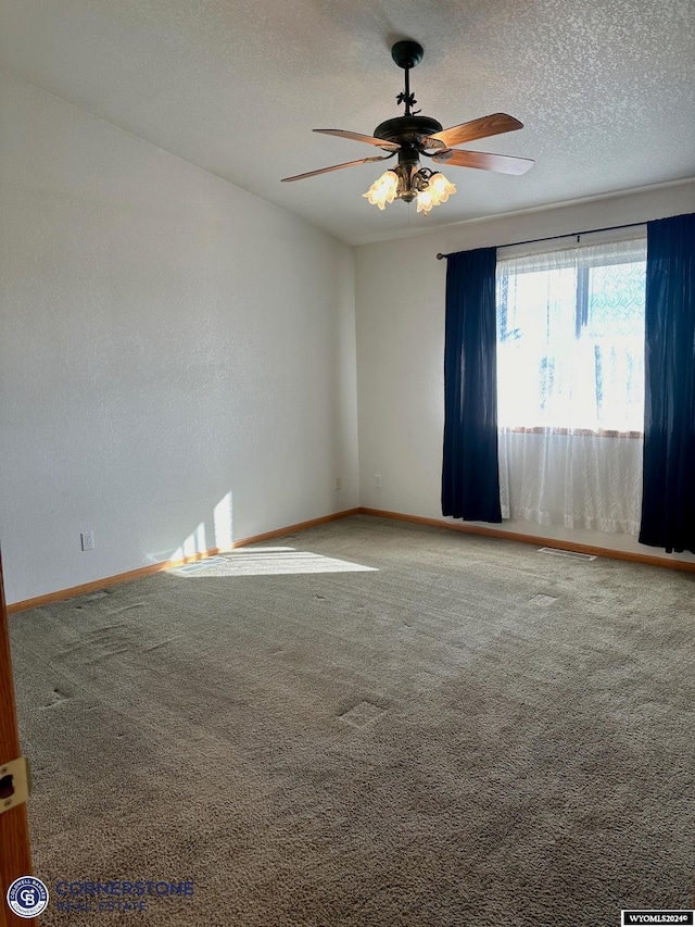 carpeted spare room with ceiling fan, baseboards, and a textured ceiling