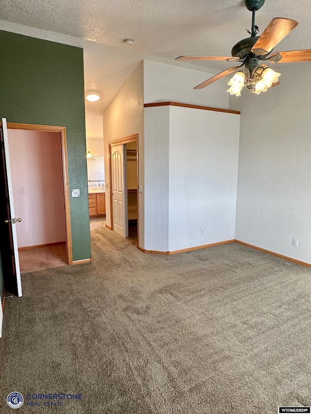 carpeted empty room with ceiling fan, a textured ceiling, and baseboards