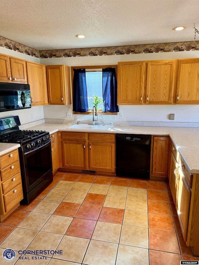 kitchen with light tile patterned floors, light countertops, a textured ceiling, black appliances, and a sink