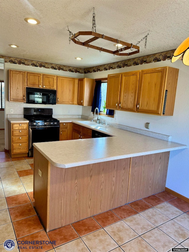 kitchen featuring light tile patterned floors, a peninsula, a sink, light countertops, and black appliances