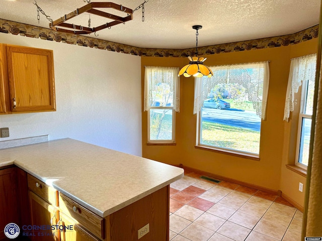 kitchen featuring a peninsula, visible vents, light countertops, and a textured ceiling