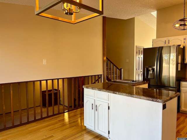 kitchen with white cabinets, a textured ceiling, light hardwood / wood-style floors, and refrigerator with ice dispenser