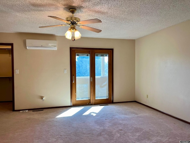 unfurnished room featuring an AC wall unit, light carpet, a textured ceiling, and ceiling fan