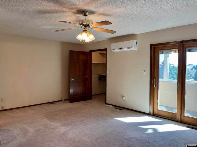 carpeted spare room featuring a wall mounted air conditioner, a textured ceiling, and ceiling fan