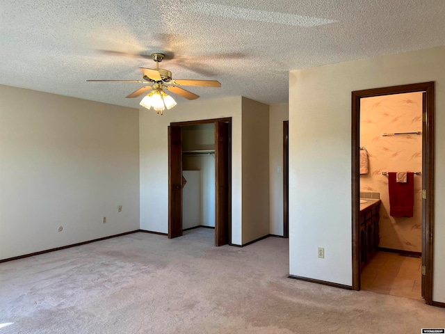 unfurnished bedroom featuring ceiling fan, a textured ceiling, light colored carpet, and ensuite bath