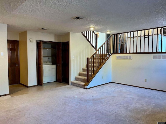 interior space featuring washer / clothes dryer, a textured ceiling, and light colored carpet