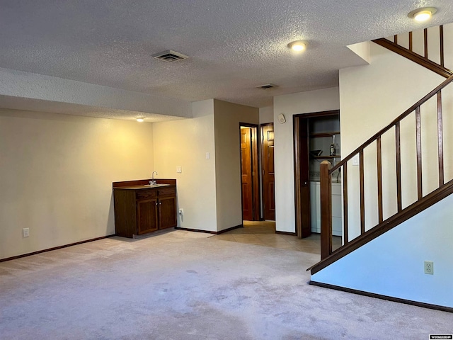 basement with a textured ceiling and light colored carpet