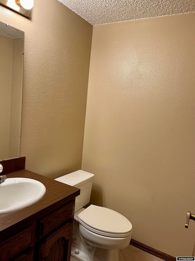 bathroom featuring toilet, a textured ceiling, and vanity