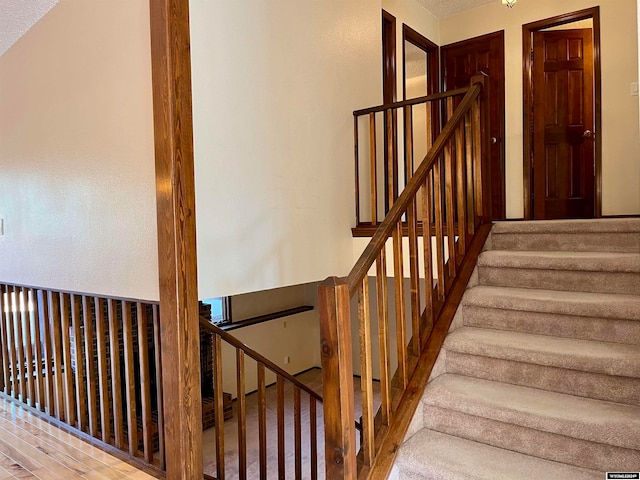 staircase with a textured ceiling and wood-type flooring