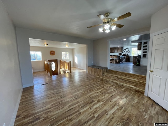 unfurnished living room with ceiling fan, wood-type flooring, and plenty of natural light