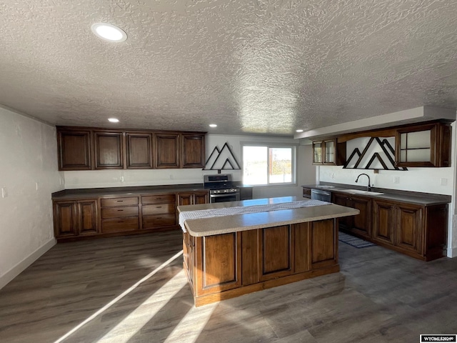 kitchen featuring appliances with stainless steel finishes, a textured ceiling, dark hardwood / wood-style floors, sink, and a center island