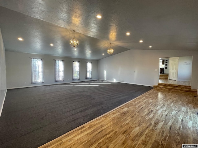 unfurnished living room with lofted ceiling, dark hardwood / wood-style floors, and a textured ceiling