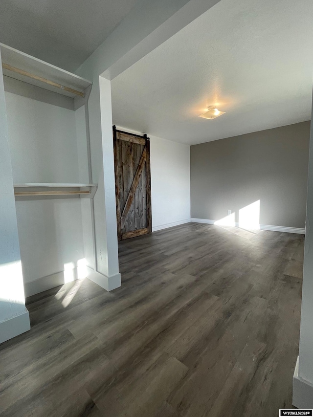 empty room featuring dark wood-type flooring and a barn door