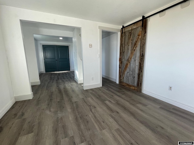 empty room featuring a barn door and dark wood-type flooring