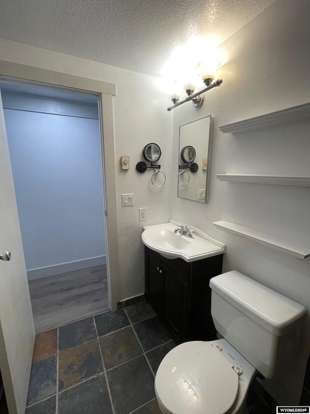 bathroom with vanity, toilet, a textured ceiling, and wood-type flooring