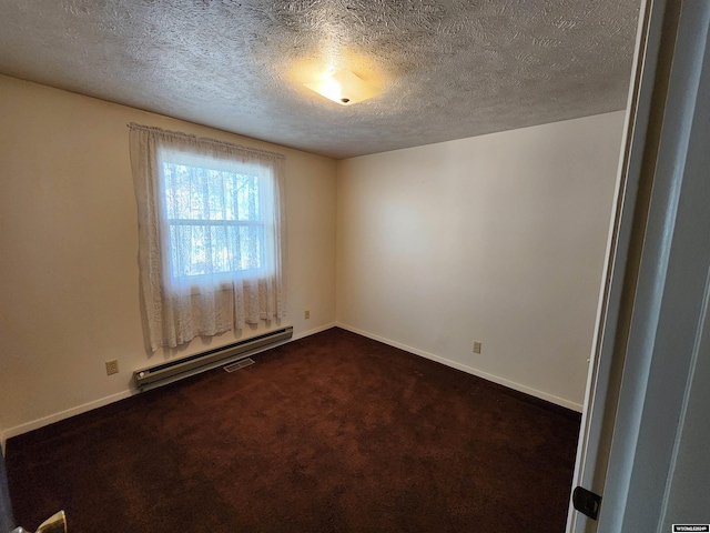 spare room featuring a baseboard heating unit, a textured ceiling, and dark colored carpet