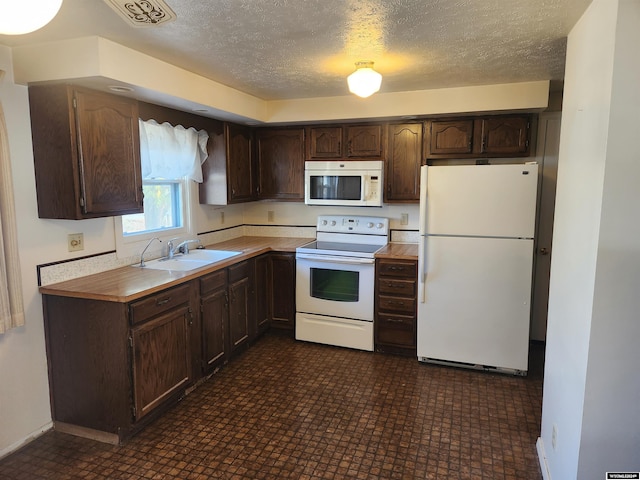 kitchen featuring a textured ceiling, sink, dark brown cabinets, and white appliances