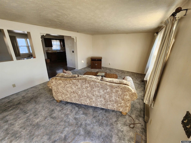 living room with a textured ceiling and dark colored carpet