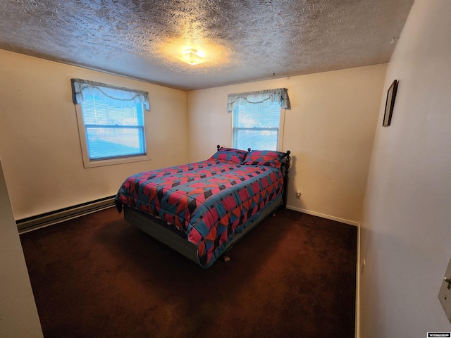 bedroom with a baseboard heating unit, dark colored carpet, and a textured ceiling