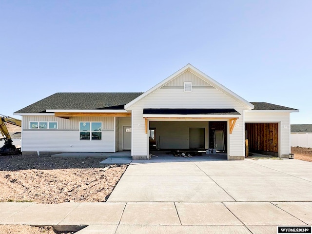 view of front of home with driveway, an attached garage, a shingled roof, and board and batten siding