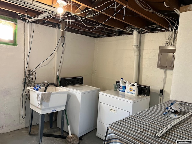 clothes washing area featuring sink, electric panel, and washing machine and clothes dryer