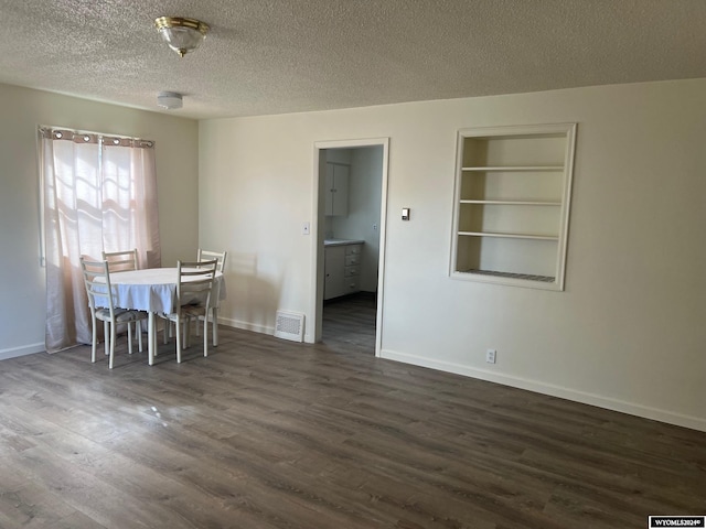 unfurnished dining area featuring a textured ceiling and dark hardwood / wood-style flooring