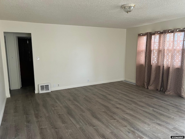 empty room featuring dark hardwood / wood-style floors and a textured ceiling