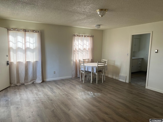 unfurnished dining area featuring a textured ceiling and dark hardwood / wood-style floors