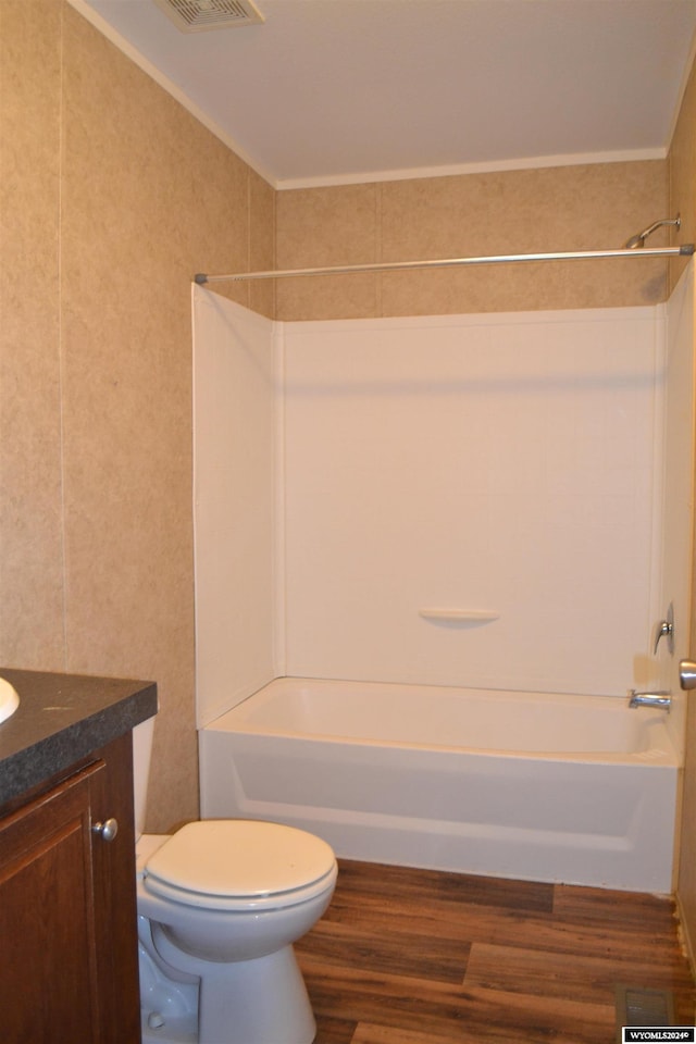 full bathroom with toilet, vanity, wood-type flooring, and washtub / shower combination