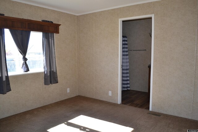 unfurnished bedroom featuring dark hardwood / wood-style floors, ornamental molding, and a walk in closet