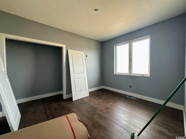 unfurnished bedroom featuring baseboards and dark wood-style flooring