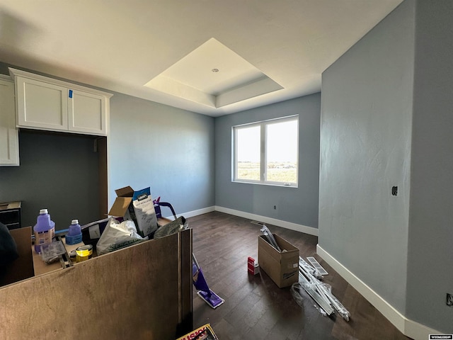 office with a raised ceiling, baseboards, and dark wood-style flooring