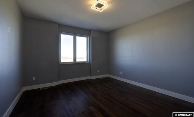 spare room featuring dark wood finished floors and baseboards