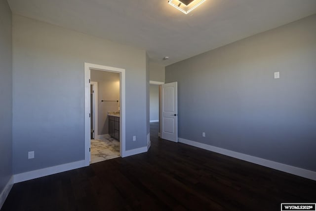 unfurnished bedroom featuring wood finished floors, baseboards, and ensuite bathroom
