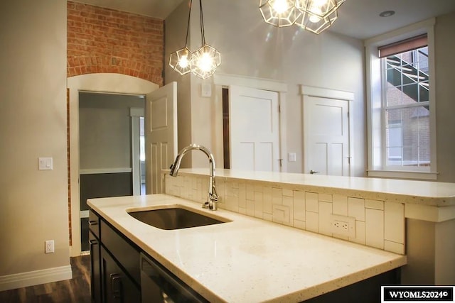 kitchen with hanging light fixtures, light stone counters, stainless steel dishwasher, dark hardwood / wood-style floors, and sink