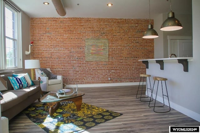 living room with brick wall and dark hardwood / wood-style flooring