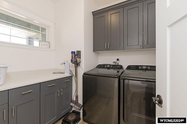 laundry room featuring separate washer and dryer and cabinets